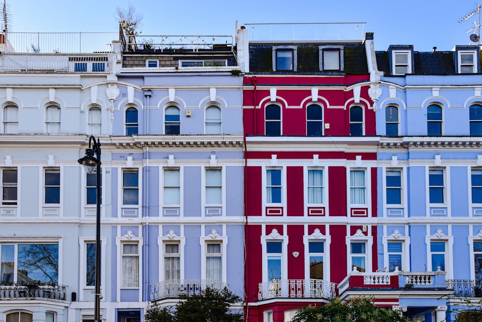 A row of Victorian terrace houses on Kirtling Street, Nine Elms, with ornate white facades, large sash windows, and decorative cornices, visible in daylight under a partly cloudy sky. In the foregroun