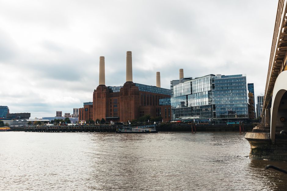 A wide view of a city skyline on the opposite bank of a river, featuring multiple modern high-rise buildings with varied architectural styles, including some with irregular window patterns and balconi
